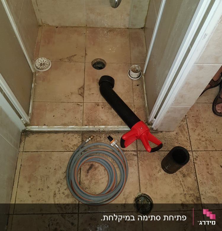 צינור מים וכלי עבודה על רצפת מקלחת